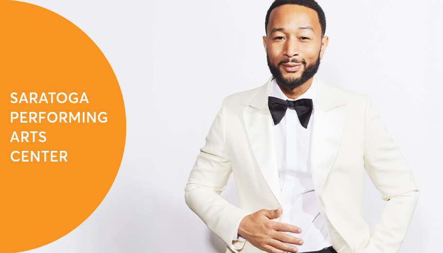 John Legend in a white suit standing against a white background