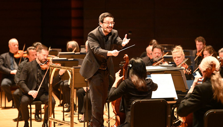 Conductor Austin Chanu conducting the Philadelphia Orchestra on stage.