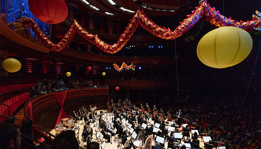 The Philadelphia Orchestra performing on stage with paper lanterns hanging above.